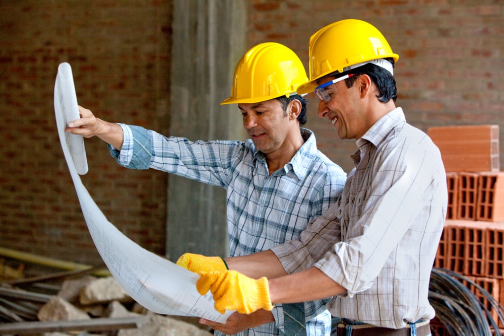 Architects at a construction site looking at blueprints Architects at a construction site looking at blueprints
